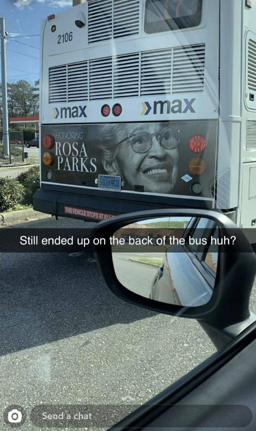Bus with Rosa Parks tribute on back, car side mirror reflecting the bus, showing a humorous moment of people knowing what they were doing.