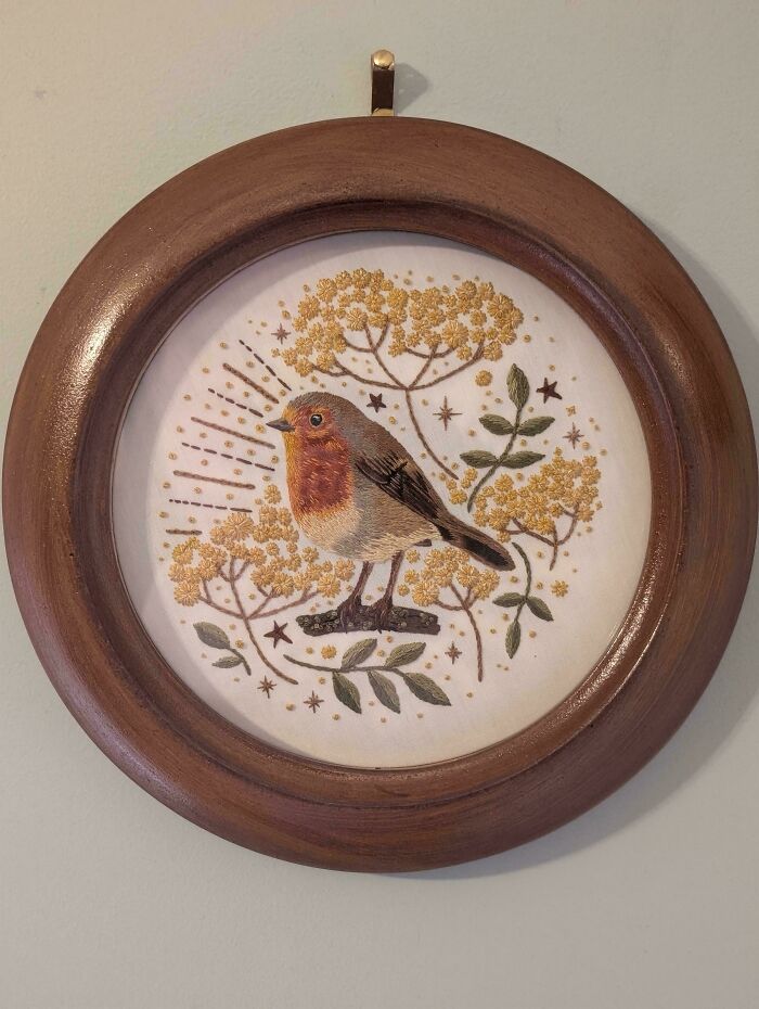 Embroidered bird with floral and star details in a round wooden frame, showcasing cottage core aesthetics decor.