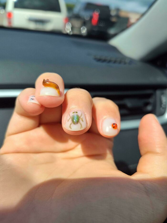 Hand with whimsical insect nail art including a snail, spider, and ladybug, showcasing cottage core aesthetics style.