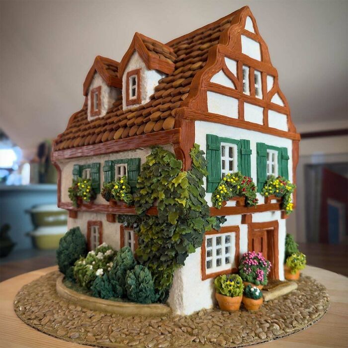 Detailed miniature cottage with greenery and flowers, showcasing charming cottage core aesthetics in a whimsical setting.