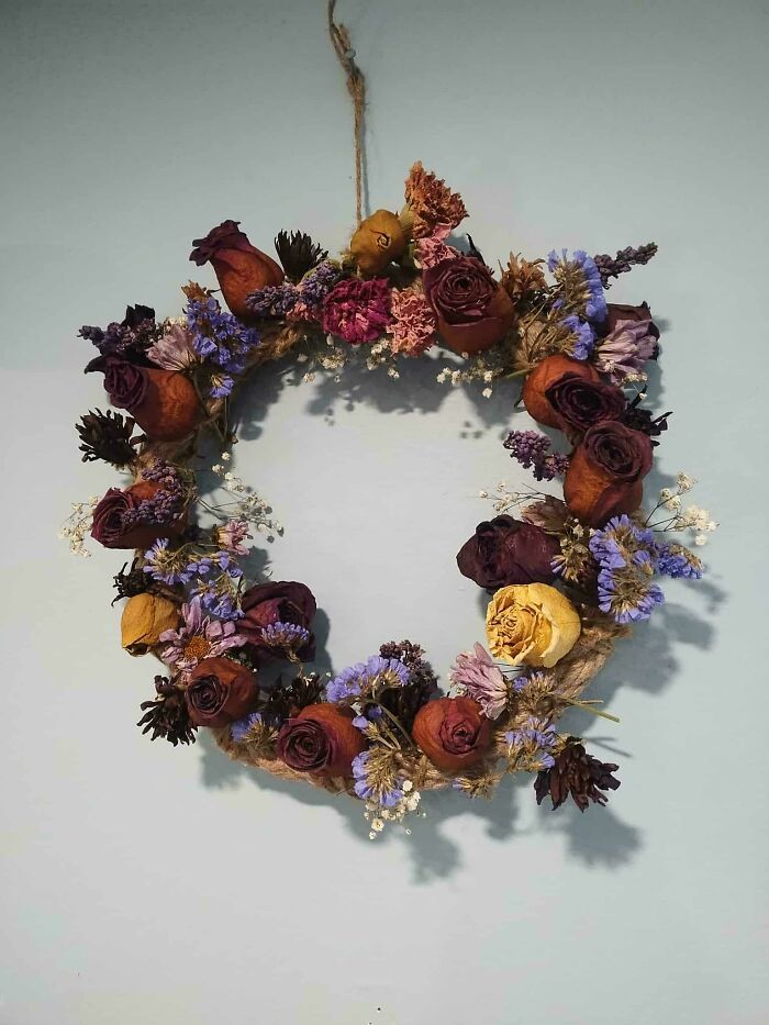 Dried flower wreath with roses and wildflowers hanging on wall showcasing cottage core aesthetics decor.