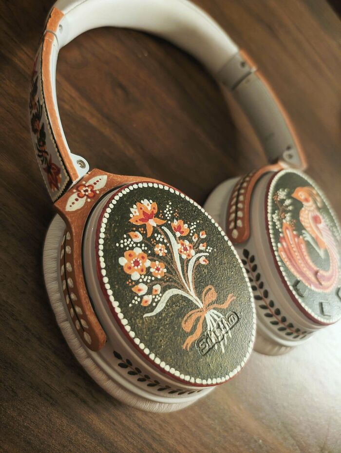 Over-ear headphones with hand-painted floral and bird designs showcasing cottage core aesthetics on a wooden surface.