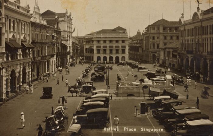 Vintage photo of Raffles Place, Singapore showing historical world capitals before modern times with old cars and colonial buildings.