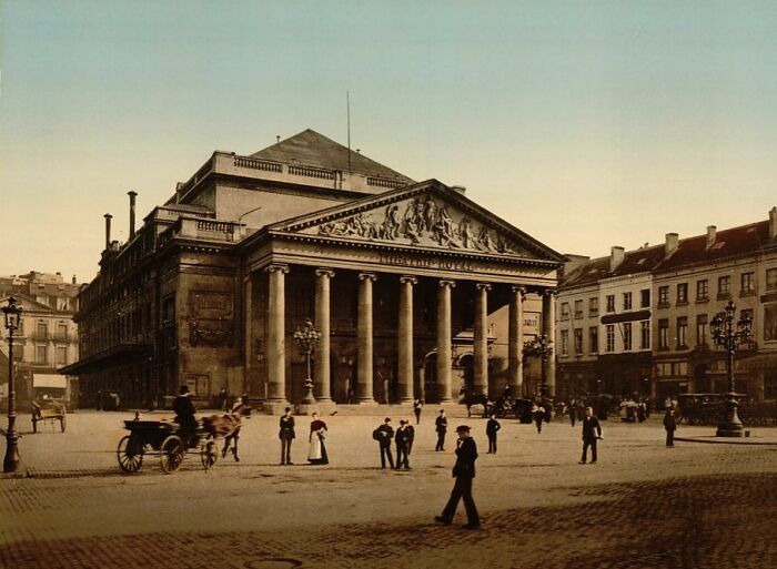 Historic photo of a world capital square with classical architecture and people before modern times in a bustling urban setting.