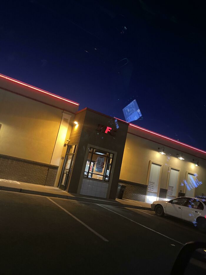 LED sign with a glowing red letter F on a building at night under a dark sky in a parking lot.