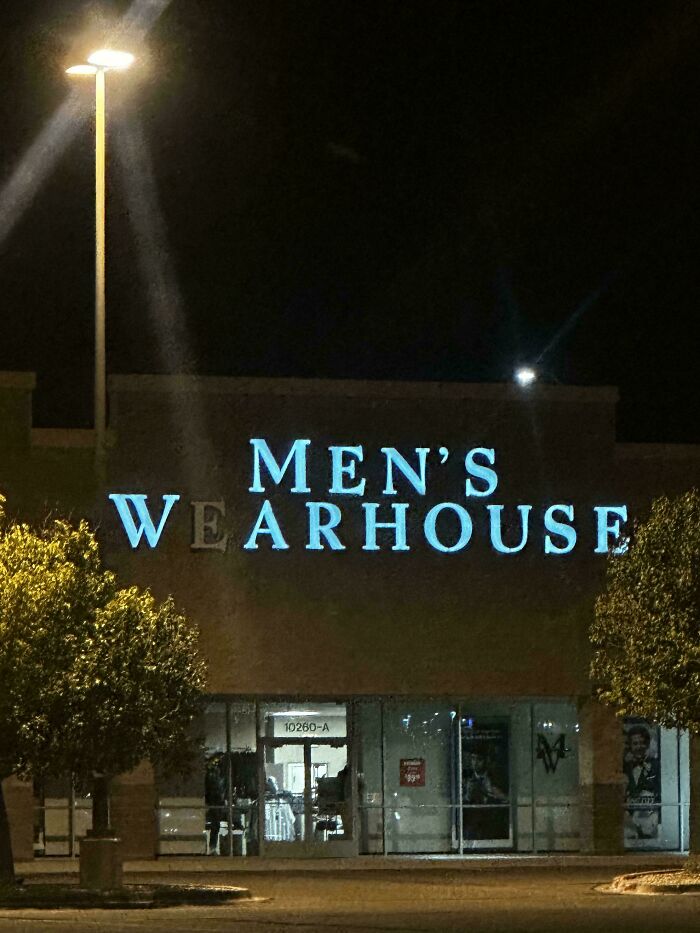 LED sign on a clothing store with partially unlit letters spelling men's wearhouse at night with streetlights nearby