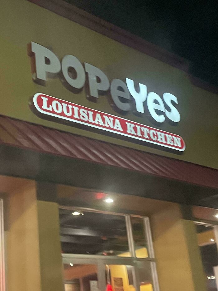 LED signs displaying the illuminated Popeyes Louisiana Kitchen logo on a restaurant exterior at night.