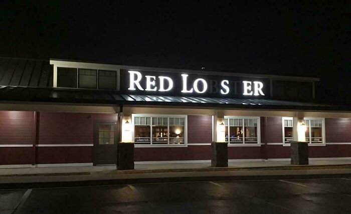 LED sign of a Red Lobster restaurant glowing at night on a building facade with visible windows and lights.