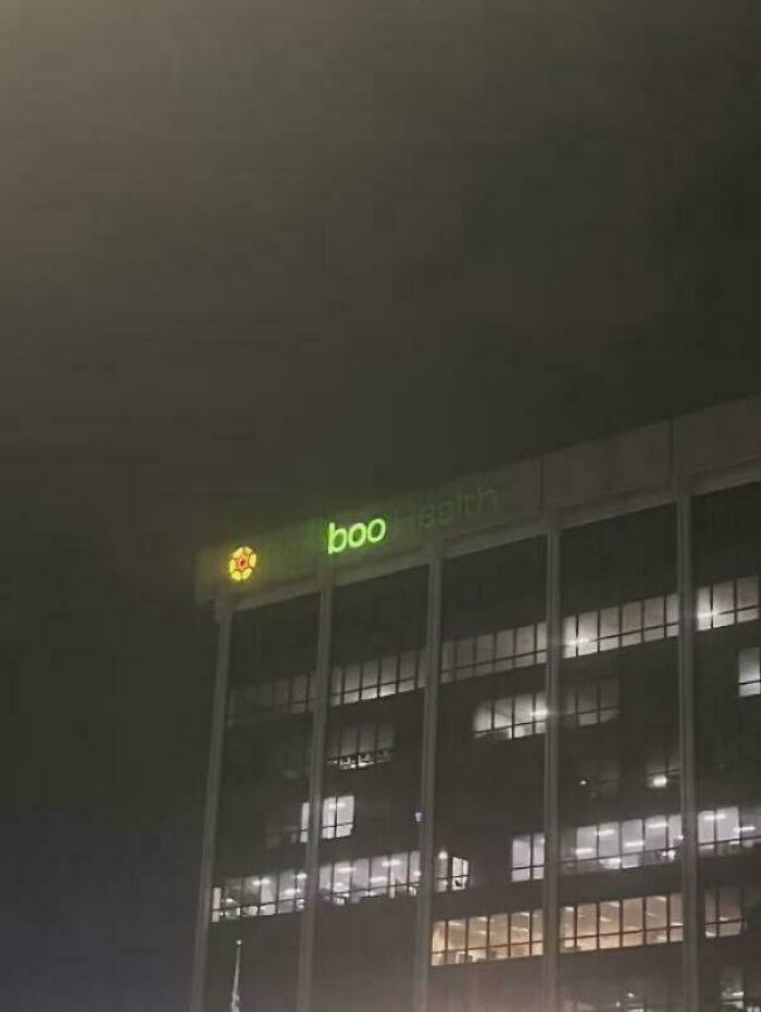 Night view of a building facade with a partially lit green LED sign displaying the word boo, an example of LED signs.
