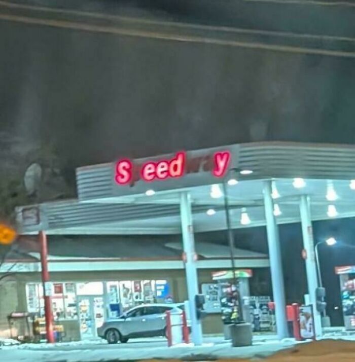 LED sign at a gas station with some letters not illuminated, showing partial word display at night.