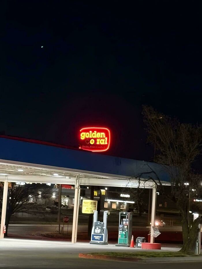 LED sign glowing red at night above a gas station with visible pumps and surrounding streetlights.