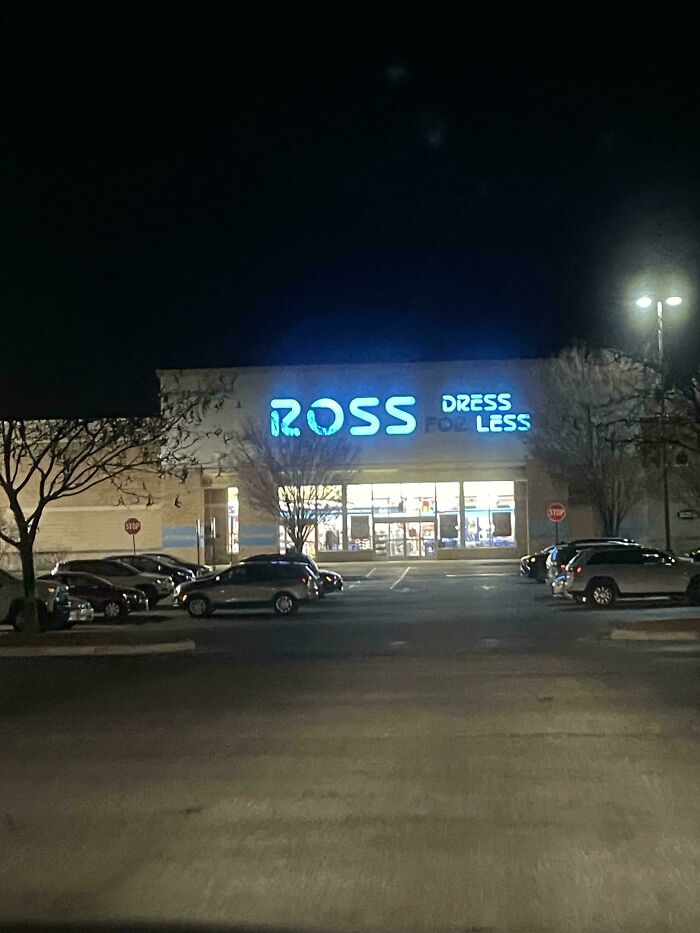 LED signs glowing bright on a retail store front at night in a nearly empty parking lot.