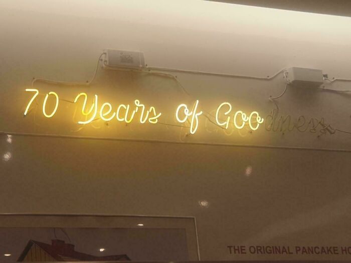 Yellow LED sign displaying the text 70 Years of Goodness mounted on a beige wall in an indoor setting.