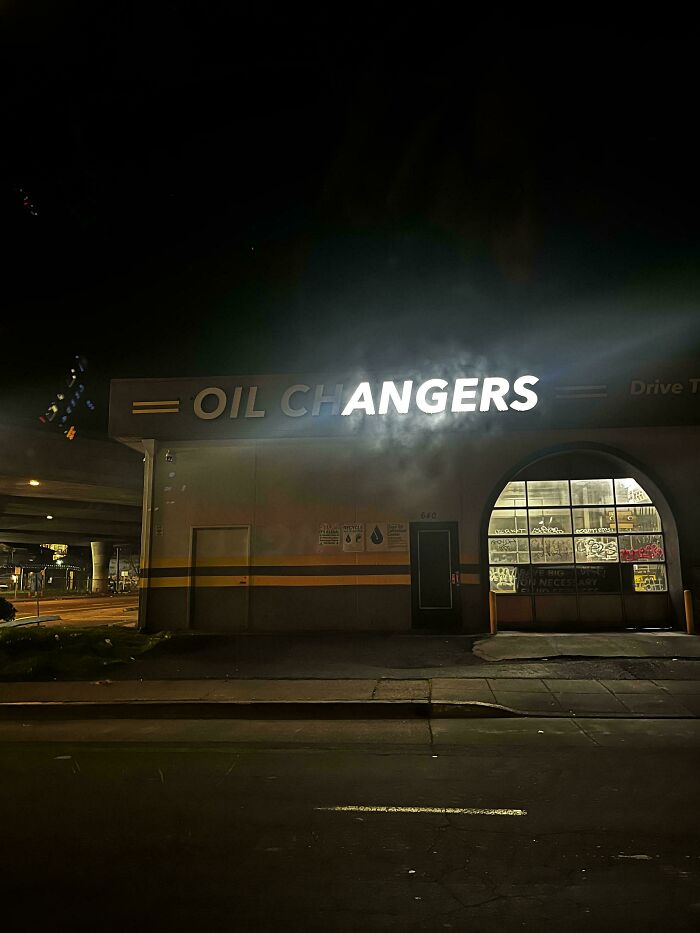 LED signs glowing at night on an oil changers service building with illuminated letters and street view nearby.