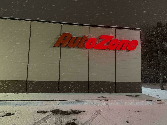AutoZone LED sign illuminated on a building exterior during snowy night, showcasing bright red LED signage.