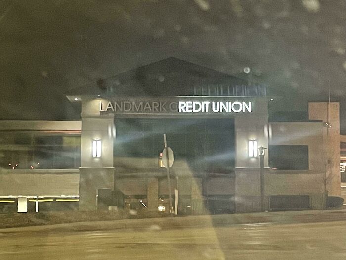 LED sign on a building at night displaying a partially lit credit union name with some letters not illuminated.