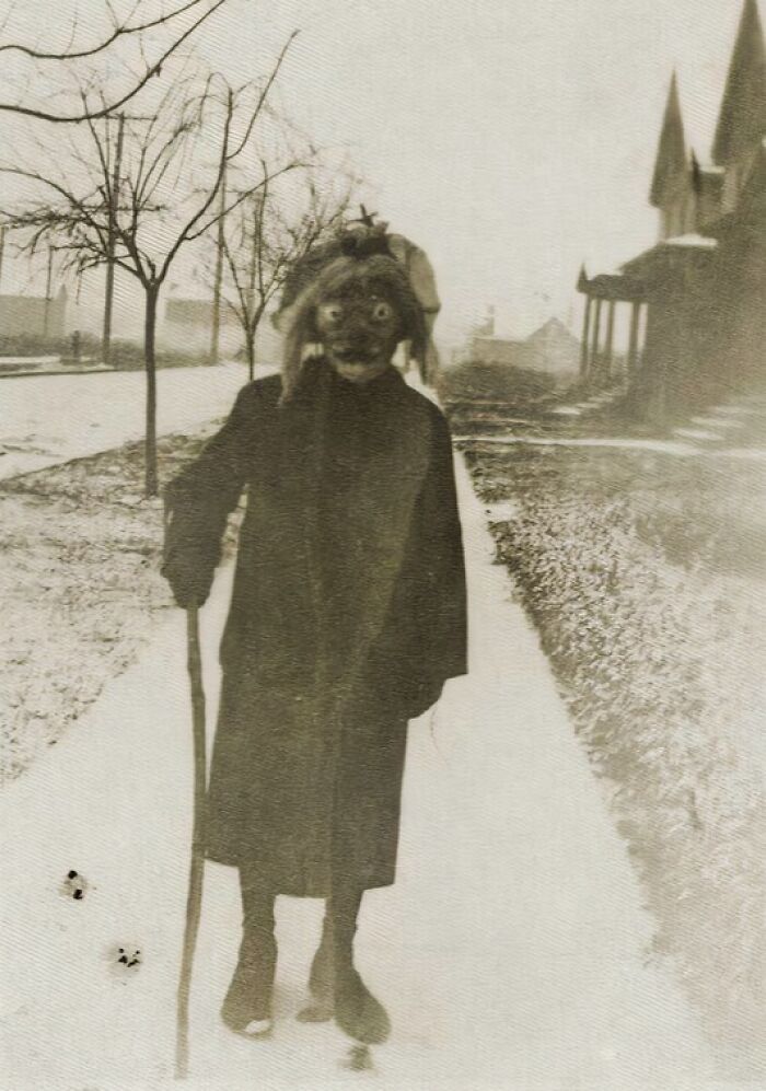 Vintage Halloween costume from the past featuring a creepy mask and walking stick on a residential street.