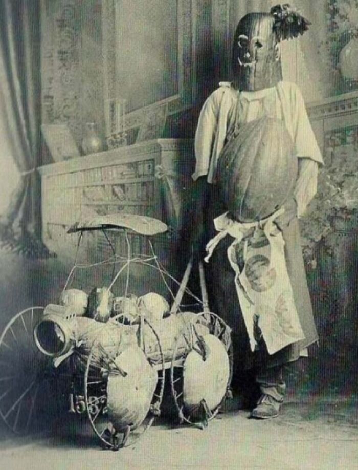 Vintage Halloween costume from the past featuring a homemade, eerie outfit and a unique mechanical cart prop.