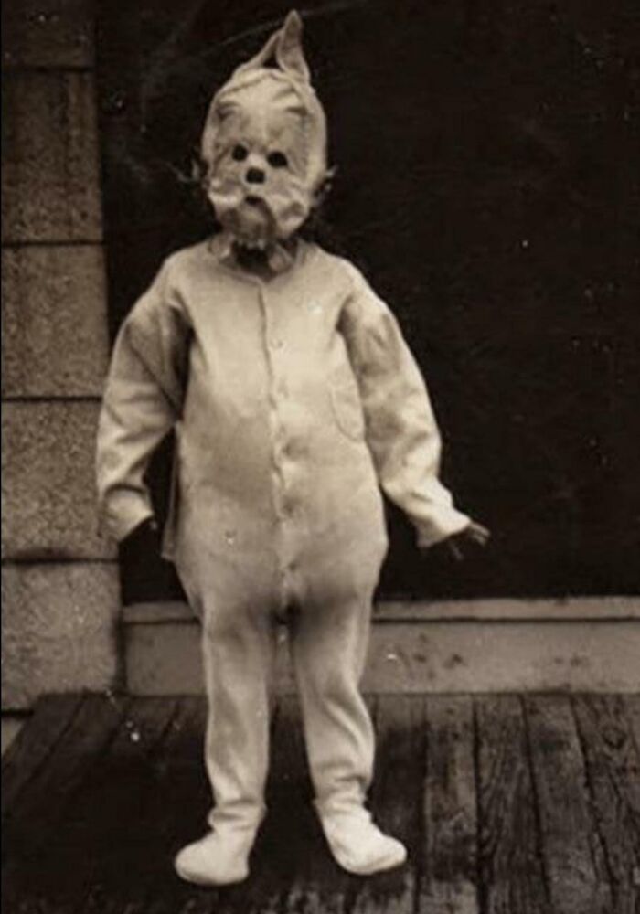 Child in a vintage Halloween costume, standing on a wooden floor, showcasing terrifying and impressive Halloween costume design.