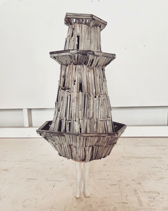 Surreal collage of a walking building with a wooden structure and human legs standing on a worn floor.