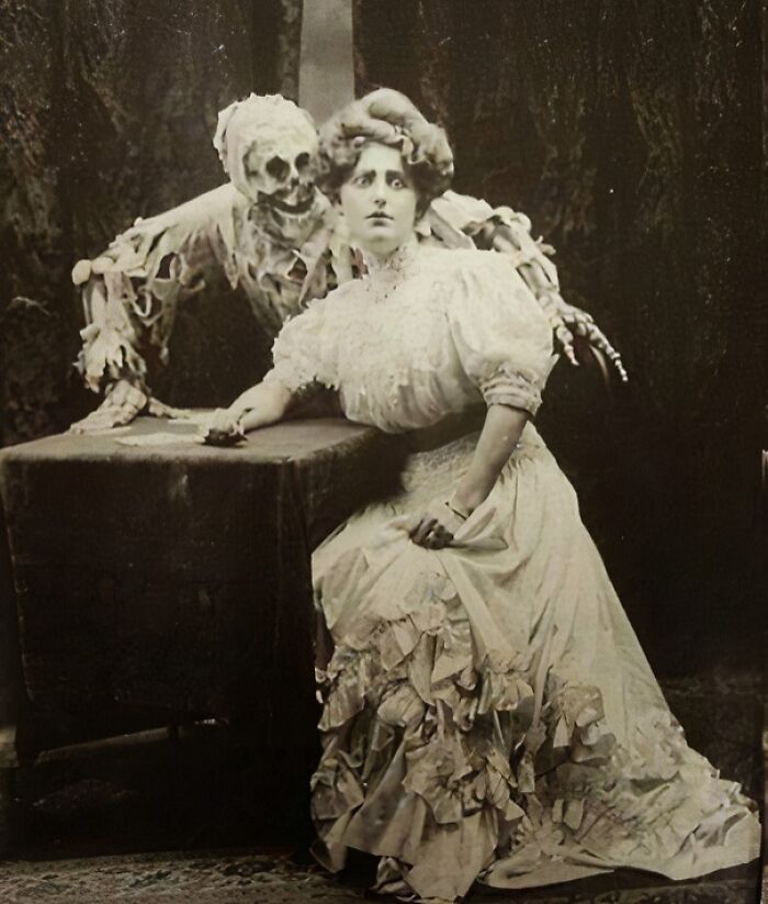 Vintage Halloween costume featuring a woman in Victorian dress with a skeleton figure behind, showcasing terrifying and impressive style.