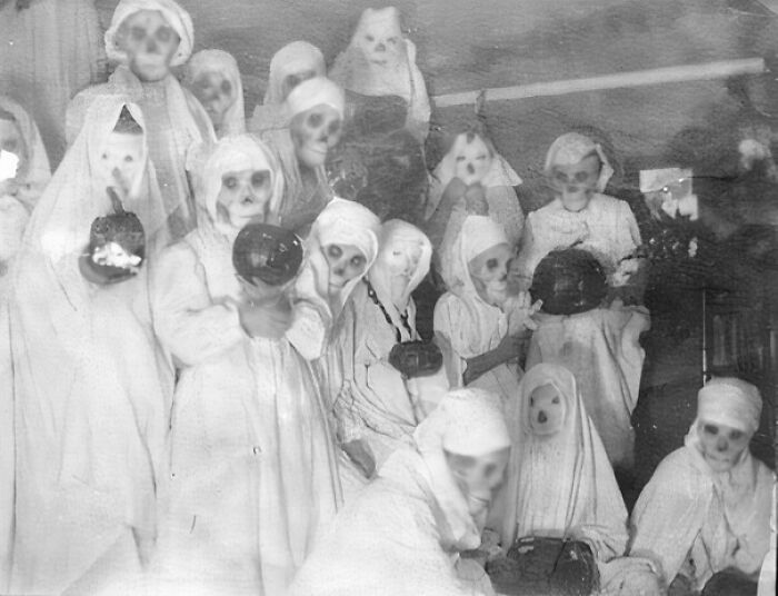 Vintage group photo of people in terrifying and impressive Halloween costumes holding pumpkins.