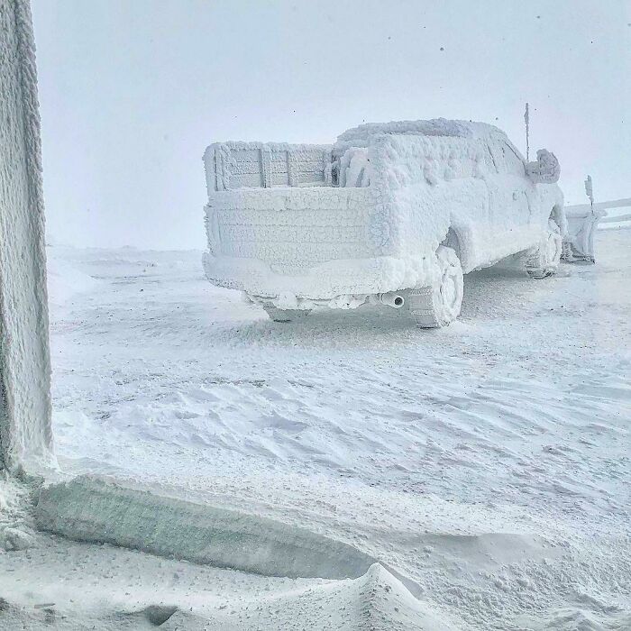 Pickup truck completely covered in snow and ice in a frozen landscape illustrating interesting pics that answer questions.