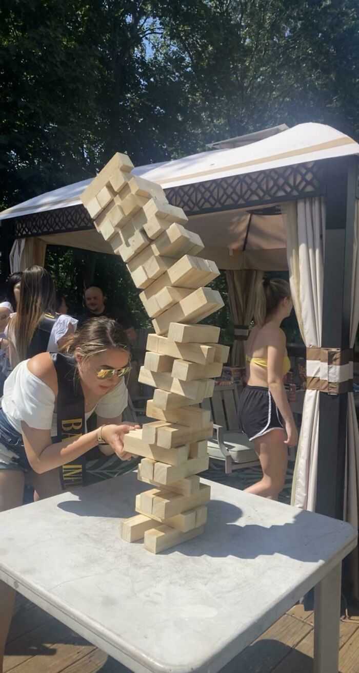 Woman playing giant Jenga as blocks start to topple during hilarious photos people managed to take before disaster struck outdoors.