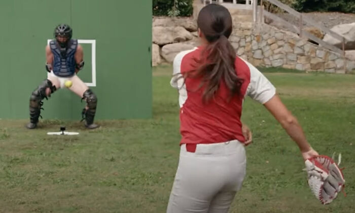 Woman pitching a ball to a catcher outdoors in a hilarious photo taken just before disaster struck.