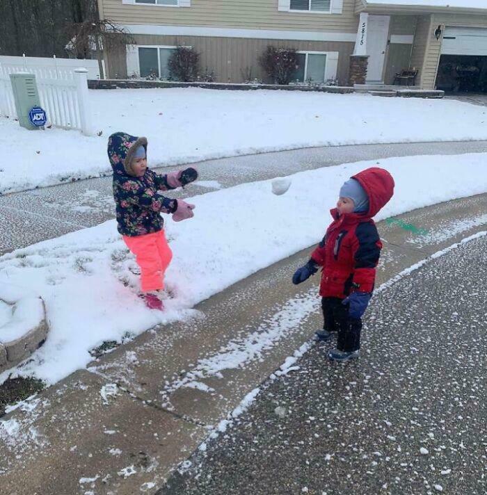 Two children outside in snow, one about to throw a snowball at the other in a hilarious moment before disaster.