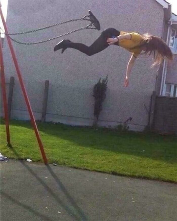 Woman falling off swing mid-air in a park, capturing a hilarious moment before disaster struck in an outdoor setting.