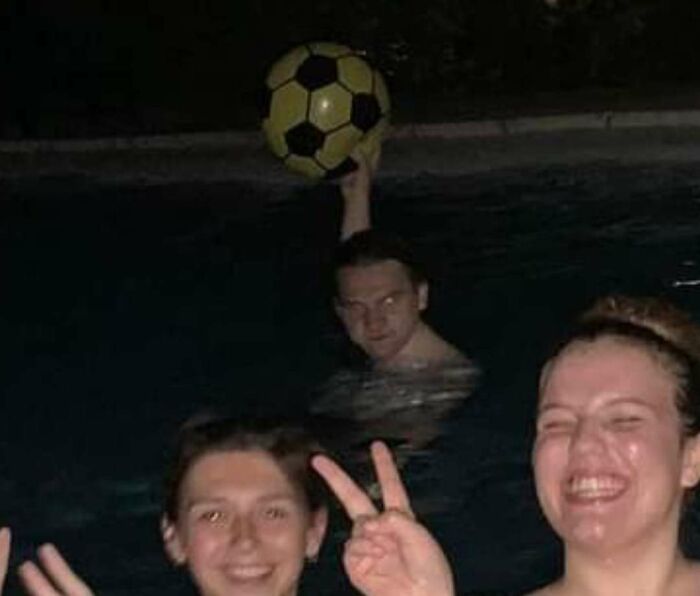 Three people smiling in a pool at night with one holding a ball ready to throw before disaster struck.