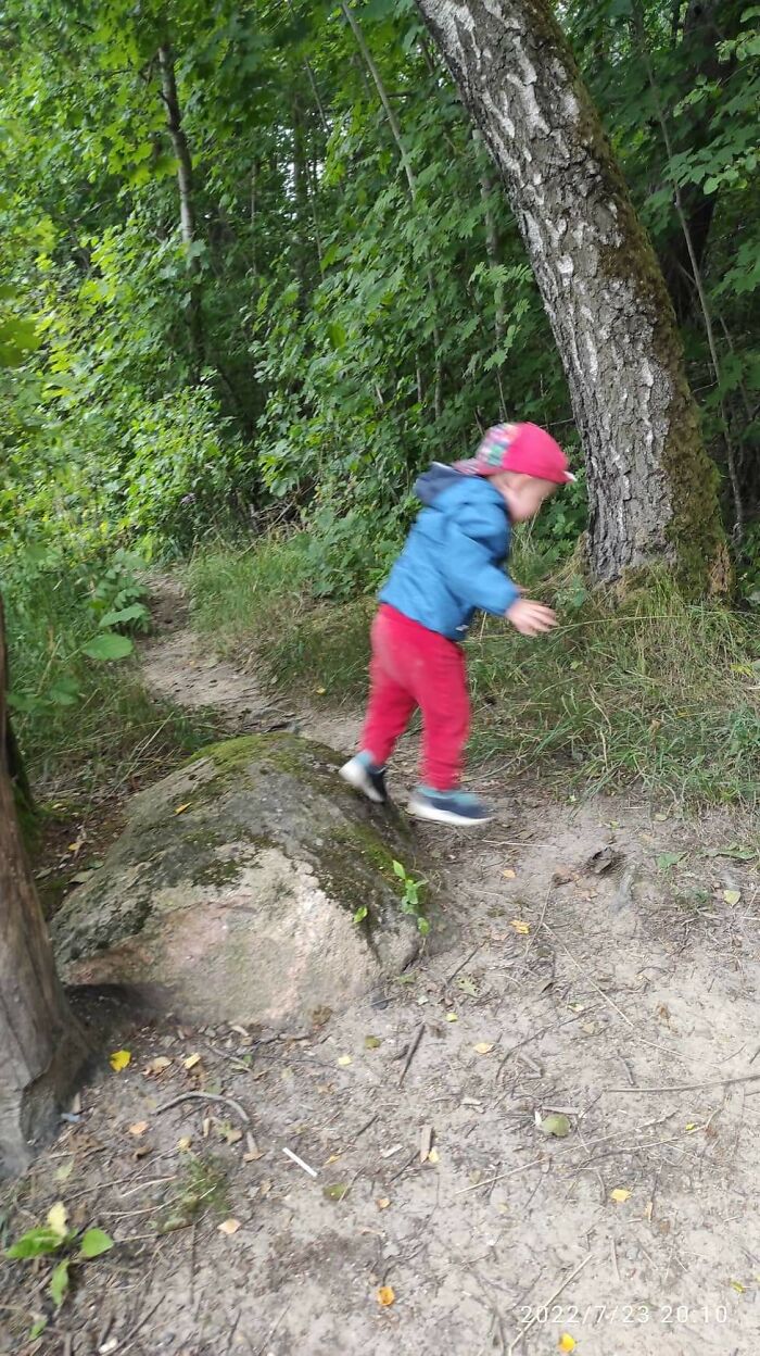Toddler in red pants about to fall while running on a forest path in a hilarious photo before disaster struck.
