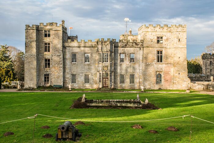 Historic stone castle with green lawn and old cannon, one of the spooky destinations for haunting Halloween visits.