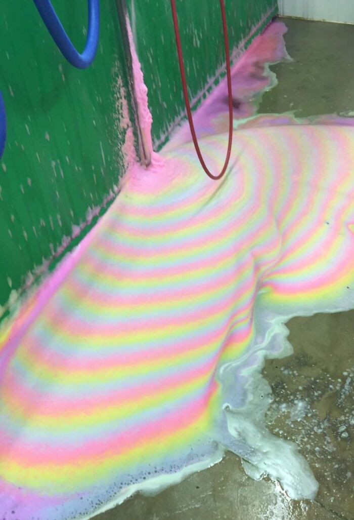 Colorful foam with rainbow patterns spreading on a concrete floor, illustrating interesting pics that answer questions.