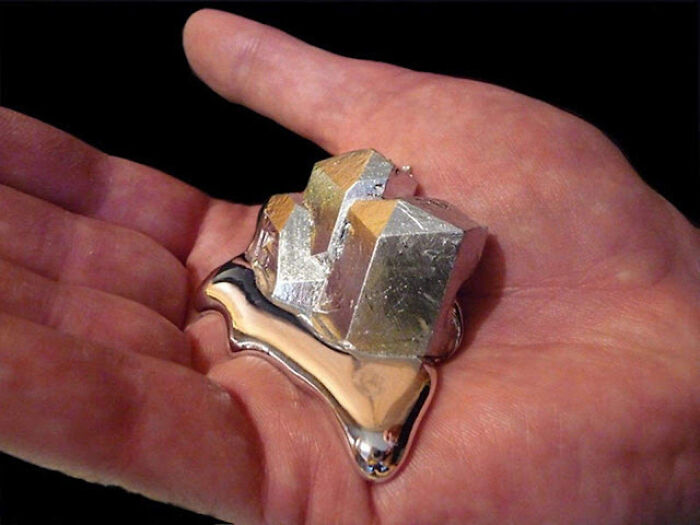 Hand holding a metallic silver crystal and liquid metal, showcasing interesting pics that answer curious questions.