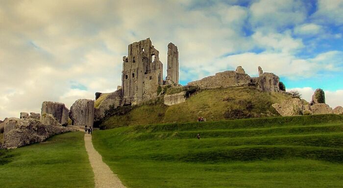 Ruins of a spooky destination with ancient stone structures on a hill under a cloudy sky, perfect for haunting visits.