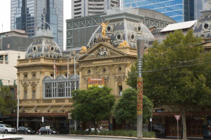 Historic theater building in a cityscape, surrounded by trees and modern skyscrapers, spooky destinations for Halloween visitors.