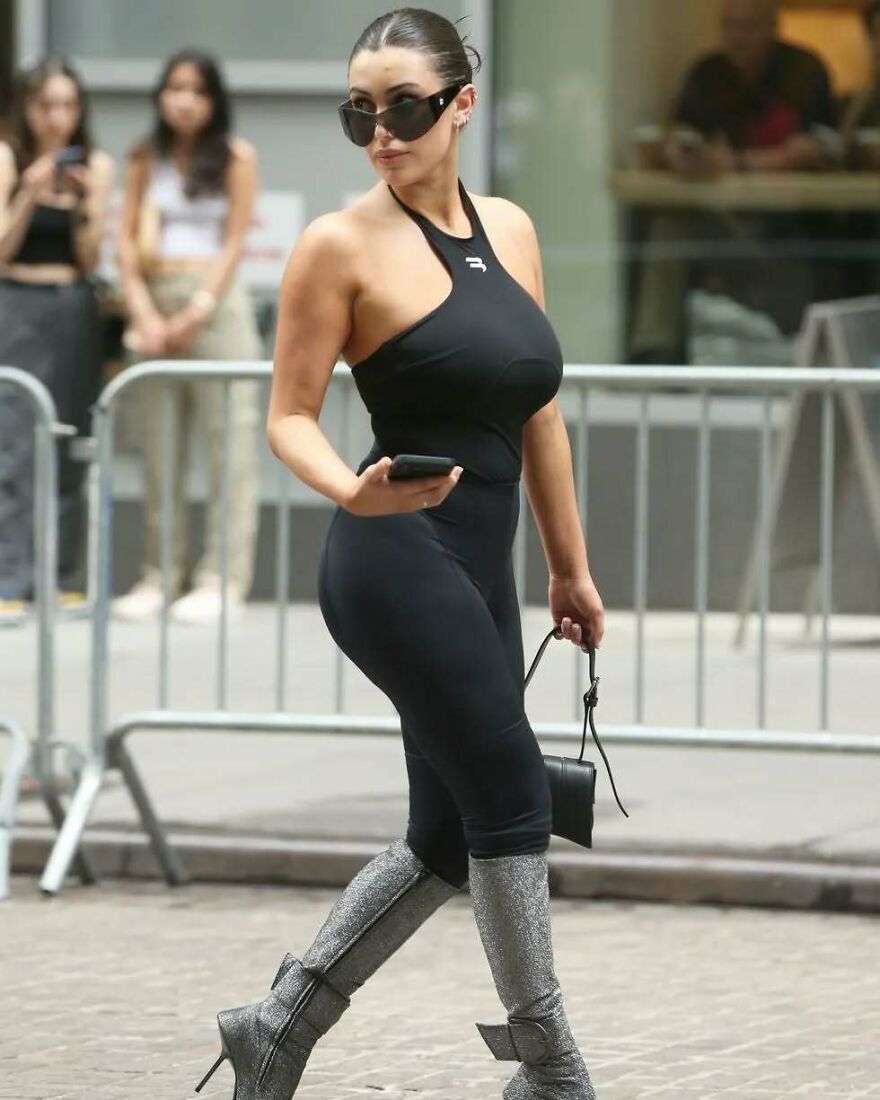 Woman in black outfit and silver boots walking on city street, representing 2024 pop culture moments that shocked readers.