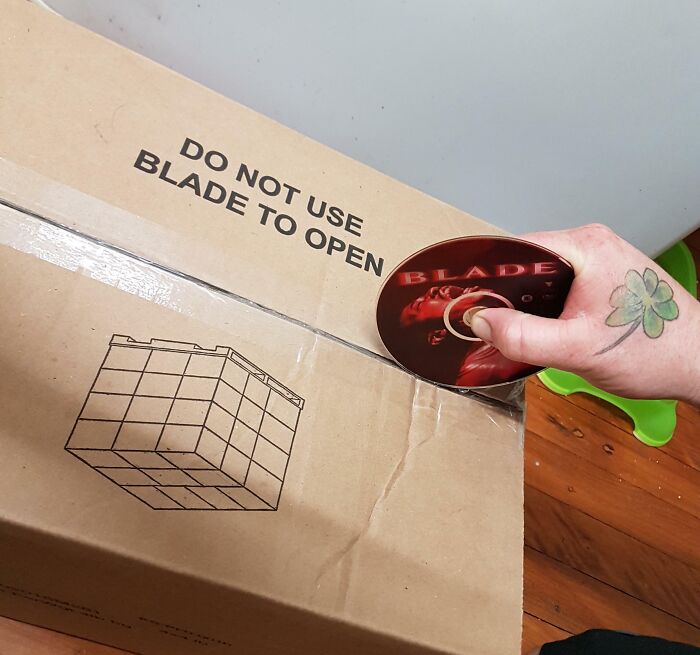 Hand holding a Blade DVD used to open a box labeled do not use blade, unhinged pics of people doing exactly what asked