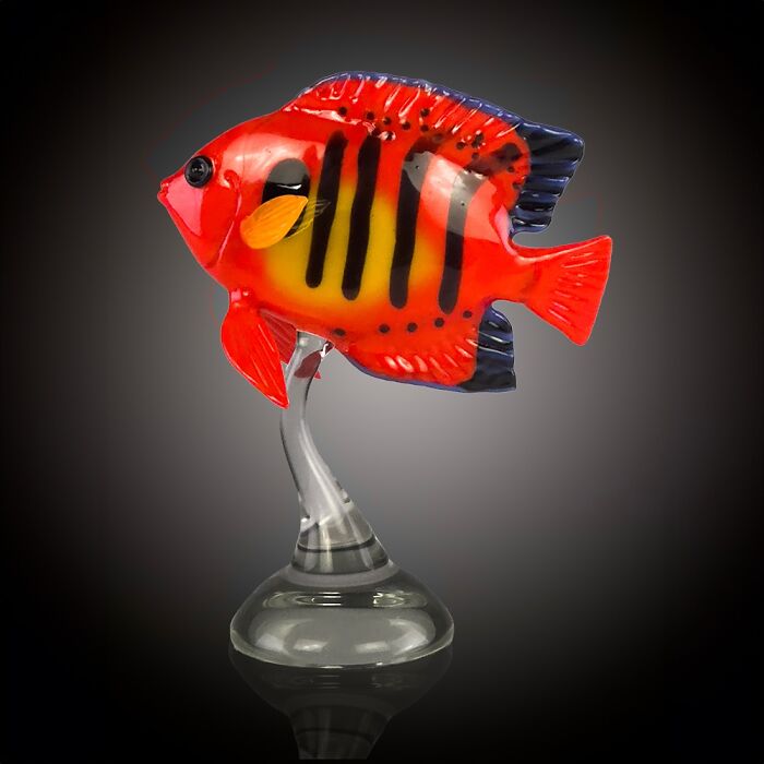 Bright red and yellow glass sculpture of a tropical fish showcasing stunning ocean life with intricate details on a clear base.