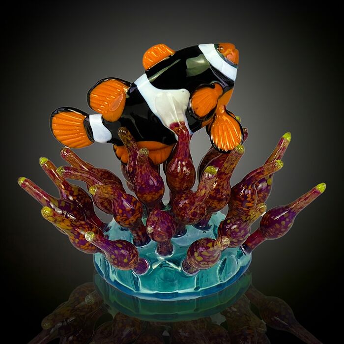 Glass sculpture of a vibrant clownfish swimming among colorful coral, showcasing stunning ocean life artistry.