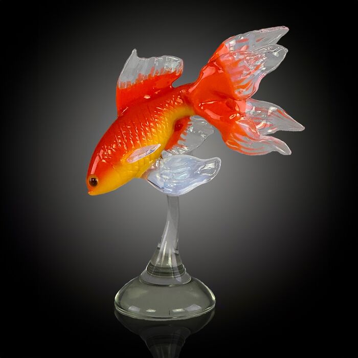 Glass sculpture of a vibrant orange and yellow fish with translucent fins, showcasing stunning ocean life artistry.