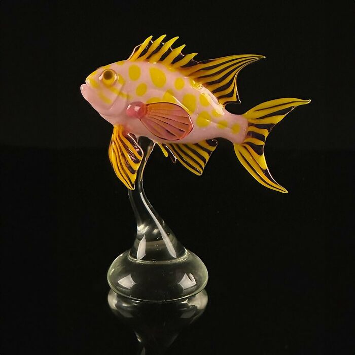 Glass sculpture of a colorful spotted fish showcasing stunning ocean life details on a clear glass stand against a black background.