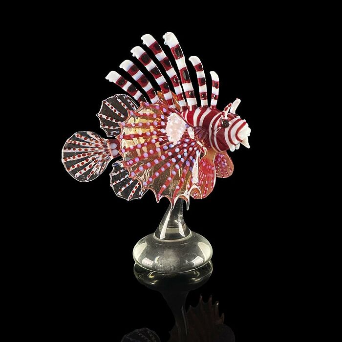 Glass sculpture of a colorful lionfish showcasing intricate details and vibrant patterns inspired by ocean life.