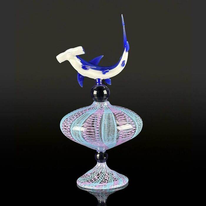 Glass sculpture of a blue and white hammerhead shark atop a detailed pastel pink and blue glass base ocean life artwork