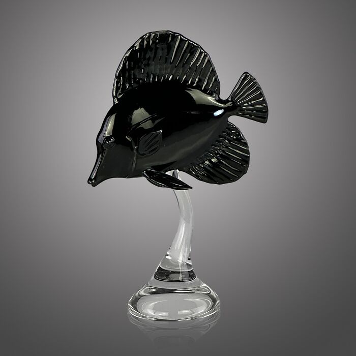 Black glass sculpture of an ocean fish on a clear glass stand, showcasing stunning glass craftsmanship and ocean life art.
