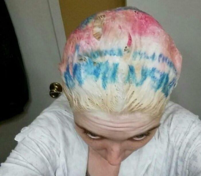 Person with a patchy, multicolored hair dye accident featuring blue, pink, and blonde tones on top of their head.