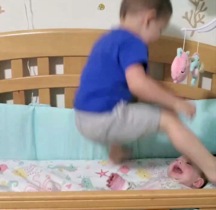 Toddler jumping on crib with baby inside in a hilarious photo captured before disaster struck.