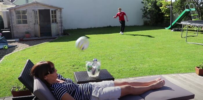 Woman relaxing on a lounge chair in backyard as a soccer ball flies toward her face, capturing a moment before disaster struck.